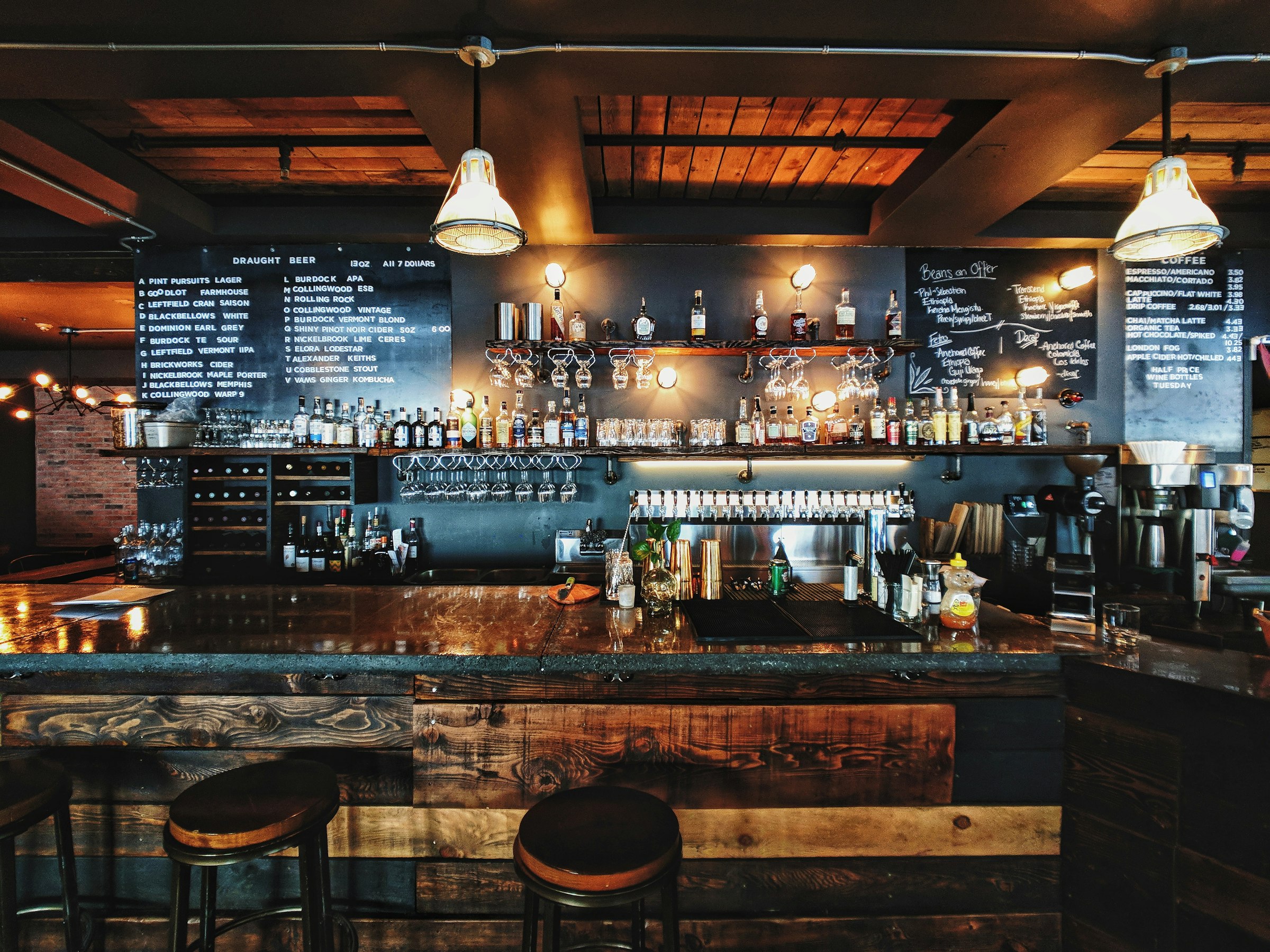 The zinc bar at night, bottles back-lit